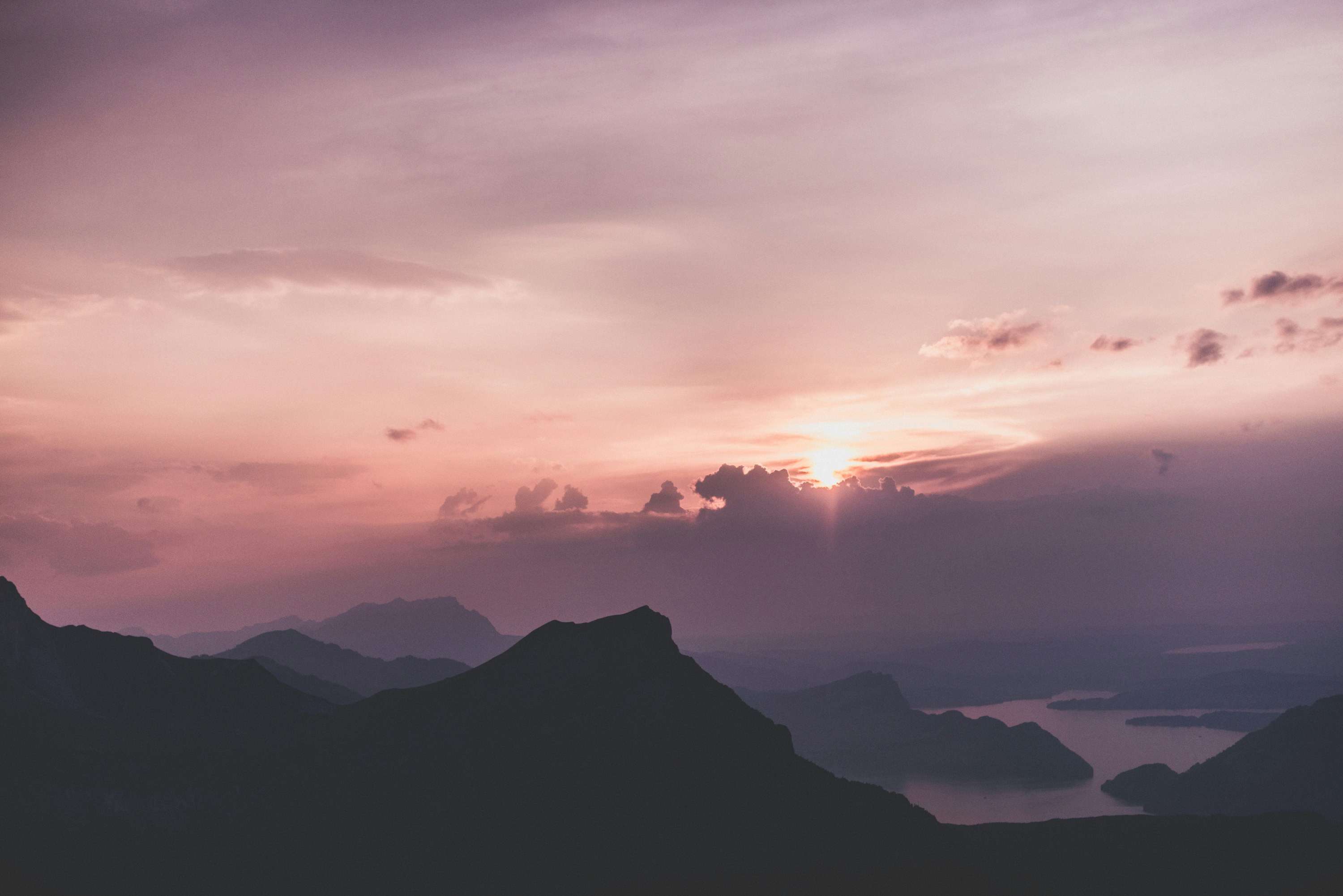 sunset, mountains, and body of water